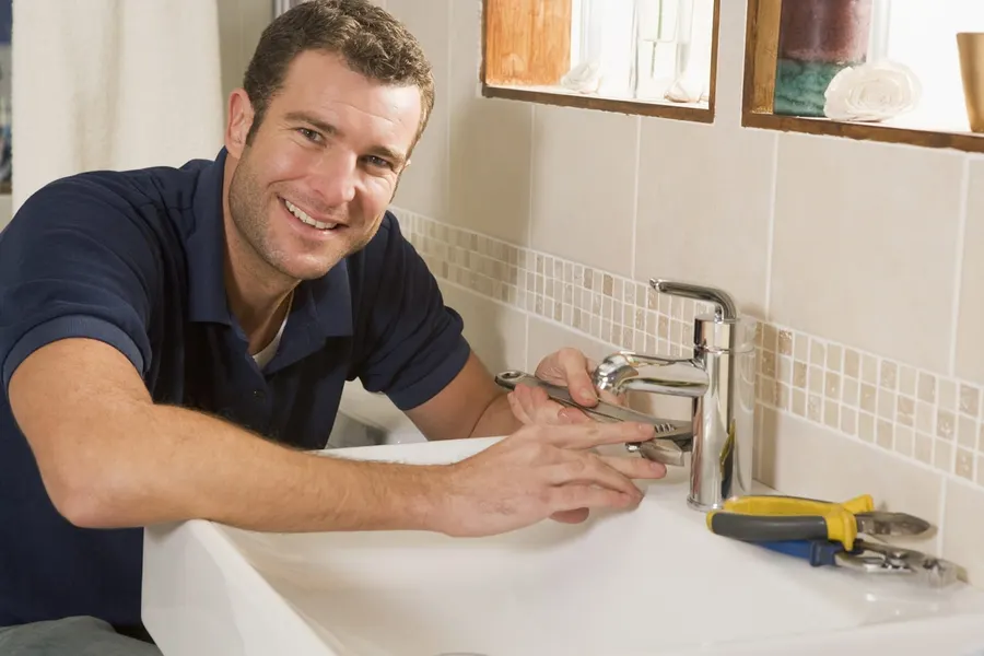 Plumber tightening a mixer tap on a bathroom basin with an adjustable wrench