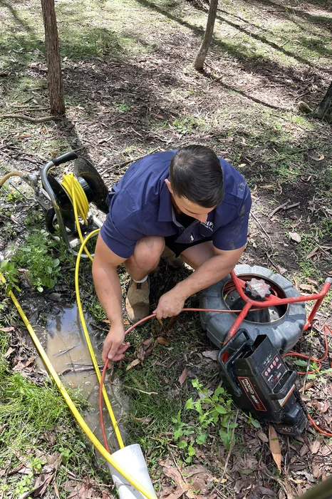 Plumber feeding a CCTV drain camera into an outdoor drain