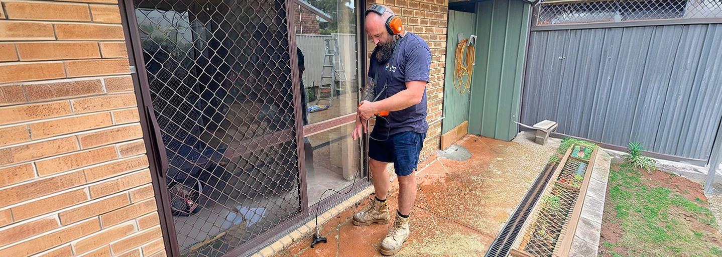 Plumber using acoustic leak detection equipment beside a house