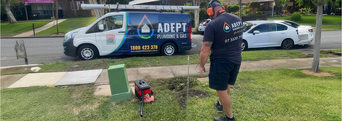 Adept Plumbing & Gas technician locating an underground pipe beside a branded van