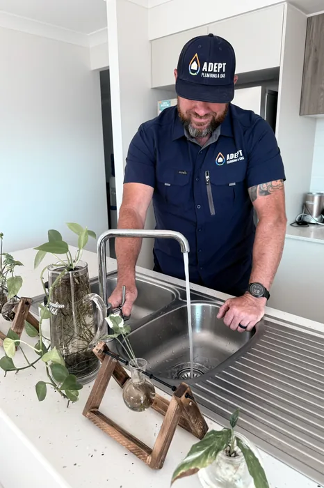 Adept Plumbing & Gas plumber checking a kitchen sink mixer tap