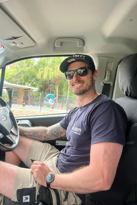 Adept Plumbing & Gas plumber smiling from the driver's seat of a work van