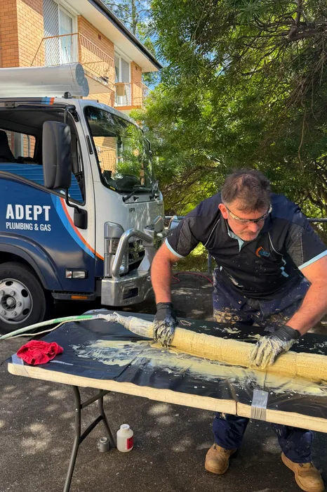 Plumber applying resin to a pipe relining patch