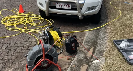 Drain cleaning machines set up beside a work ute on a Calamvale street