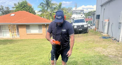 Adept Plumbing & Gas plumber locating a drain line on a Calamvale lawn