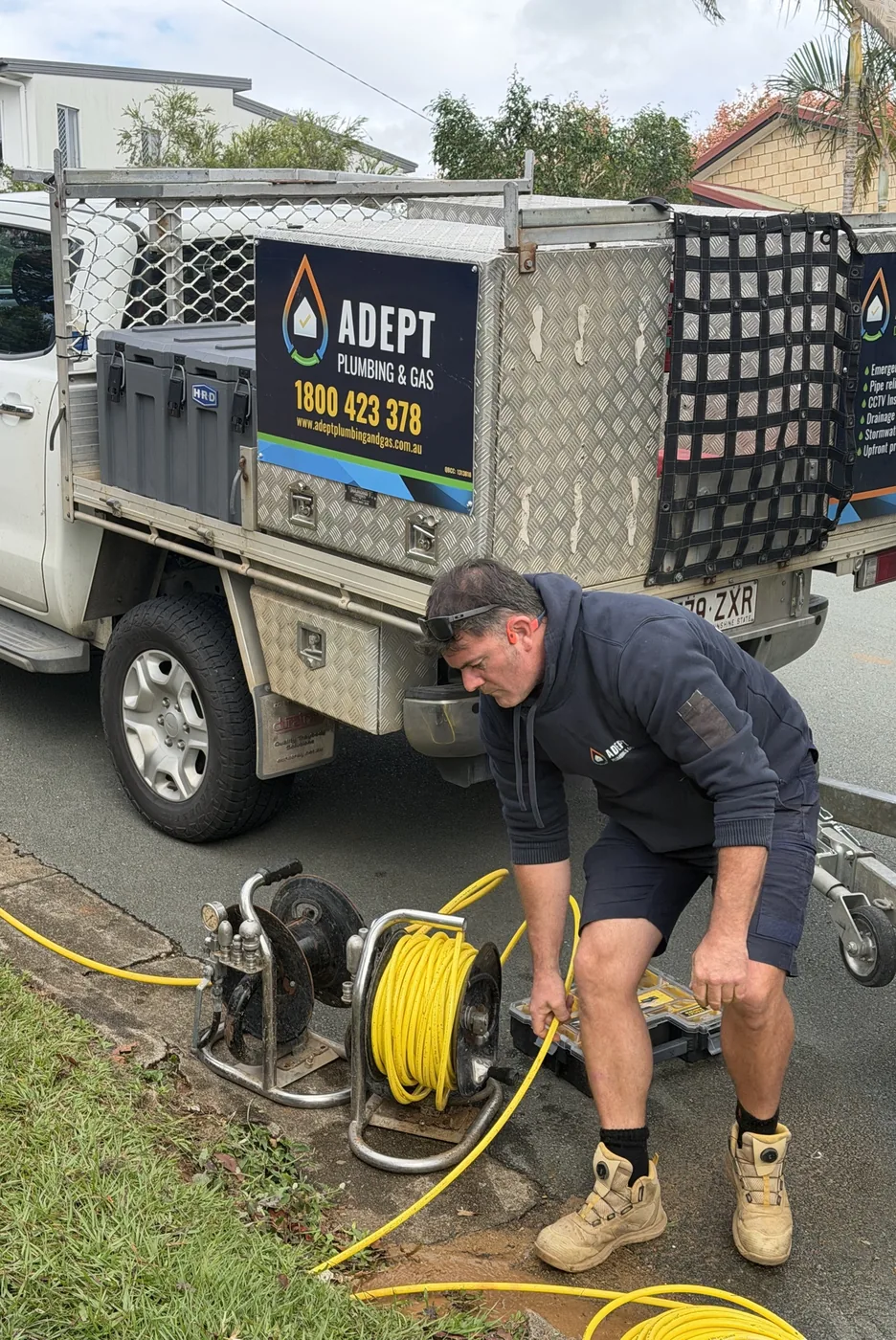 Adept Plumbing & Gas plumber setting up the drain jetter beside the ute in Cornubia