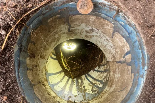 Open drainage pipe in the ground during a plumbing job in Logan