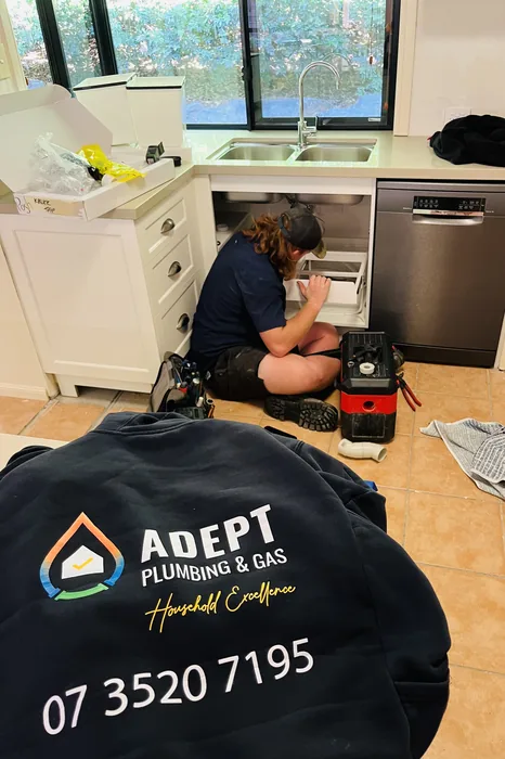 Adept Plumbing & Gas plumber connecting a dishwasher under a kitchen bench