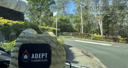 Adept Plumbing & Gas branded cap resting on a coiled rope in Tanah Merah
