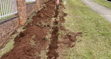 Trench dug for new pipework along a fence at a Tanah Merah property