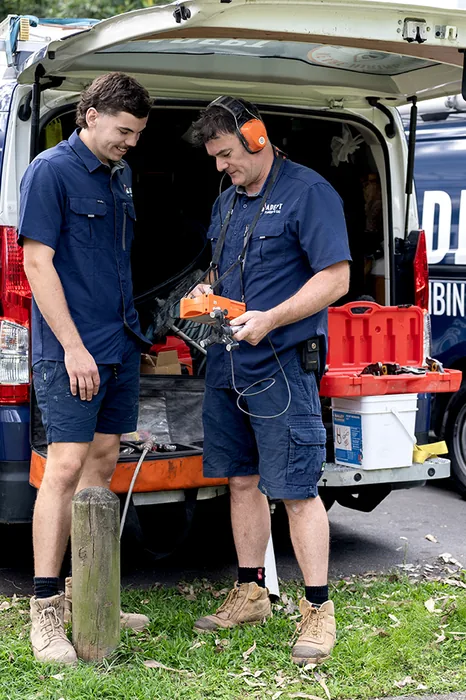 Two Adept Plumbing & Gas plumbers at the back of their service vans