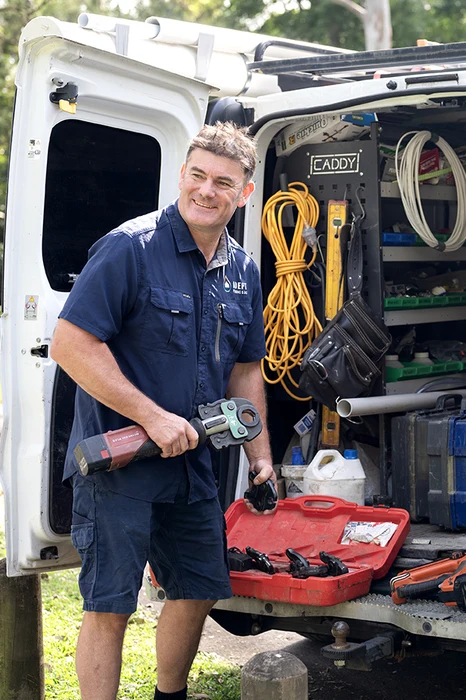 Adept Plumbing and Gas plumber at the open rear of a fully stocked service van