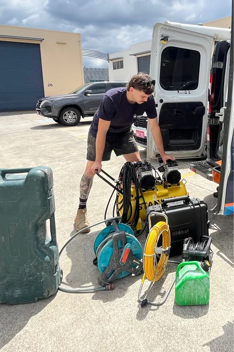 Adept Plumbing and Gas technician unloading testing equipment from a service van