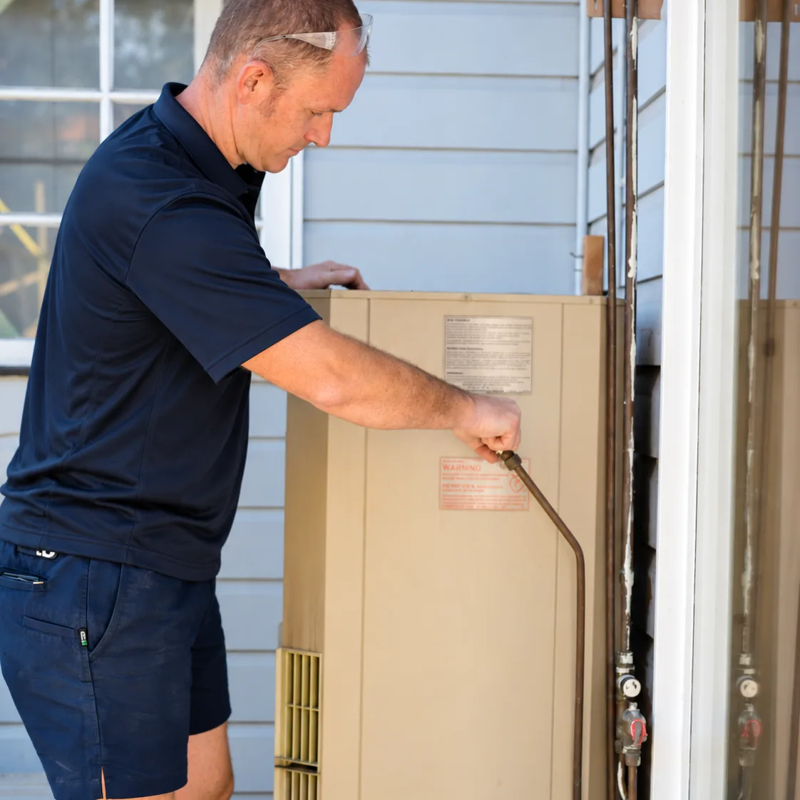 Adept Plumbing & Gas plumber servicing a gas hot water unit