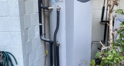 Heavy-duty natural gas storage hot water system installed beside a block wall