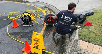Plumber jetting a blocked drain behind safety cones in Camp Hill