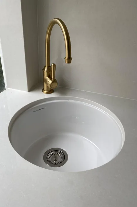 Brushed brass sink mixer above a round basin in Cornubia