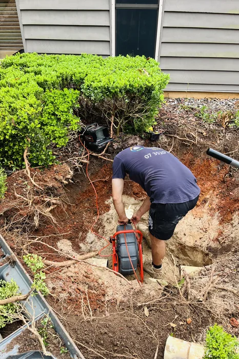 Plumber repairing a drain in an excavated pit in Holland Park