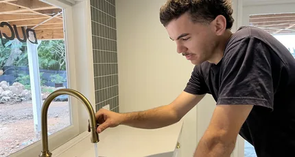 Plumber testing a brushed brass kitchen mixer in Holland Park