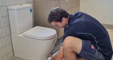 Plumber installing a toilet in a Loganholme bathroom