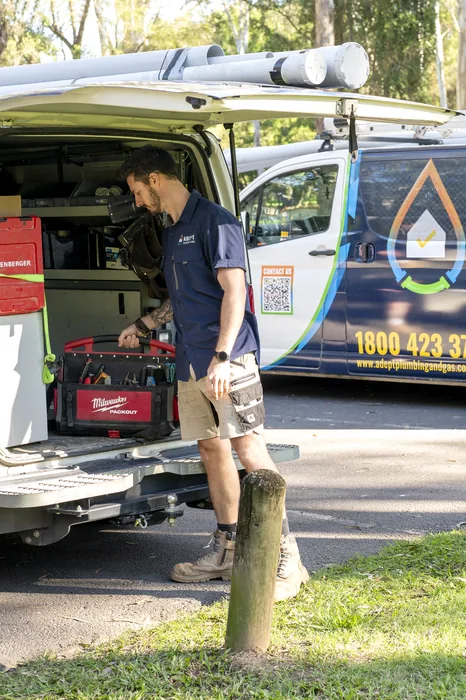 Adept Plumbing & Gas plumber loading tools from a company van in Marsden