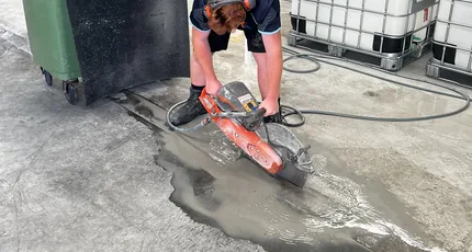 Plumber cutting a concrete floor to reach pipework on a Meadowbrook job