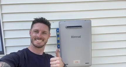 Plumber beside a newly installed Rinnai continuous flow hot water system in Meadowbrook