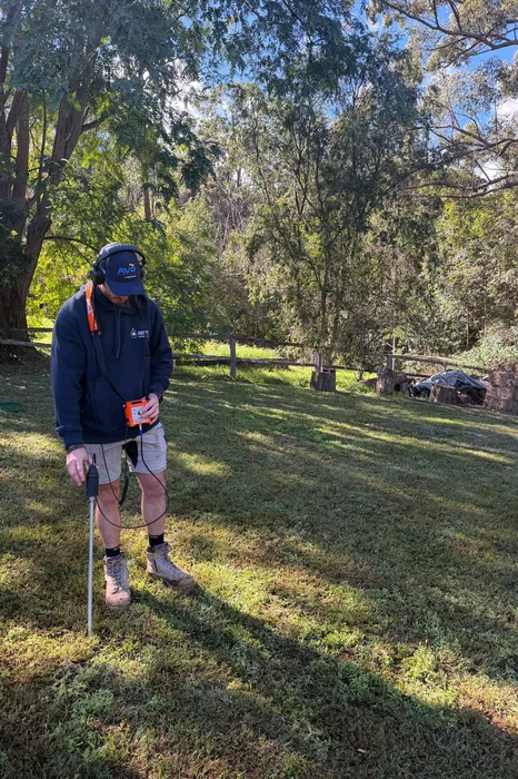 Plumber using acoustic leak detection equipment in a yard in Springwood