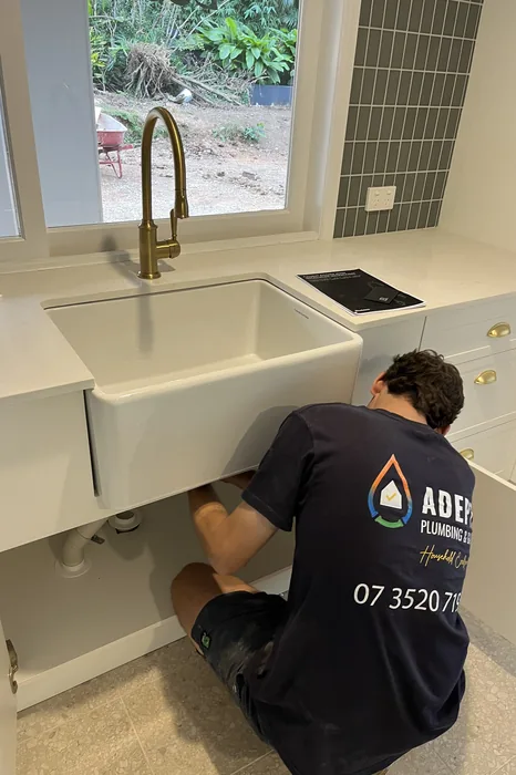 Plumber installing a butler sink and brass mixer in Waterford