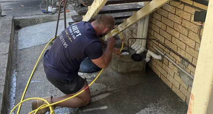 Plumber clearing a drain beside a home in Waterford