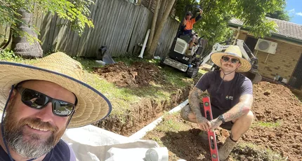 Plumbers laying new drainage in a backyard trench in Waterford