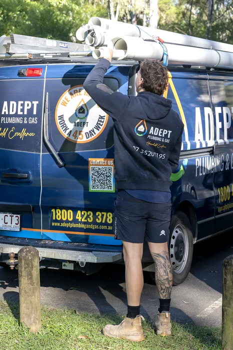 Adept Plumbing & Gas plumber unloading pipe from a company van in Waterford