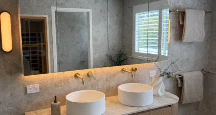 Renovated bathroom with a double vanity and backlit mirror by Adept Plumbing & Gas