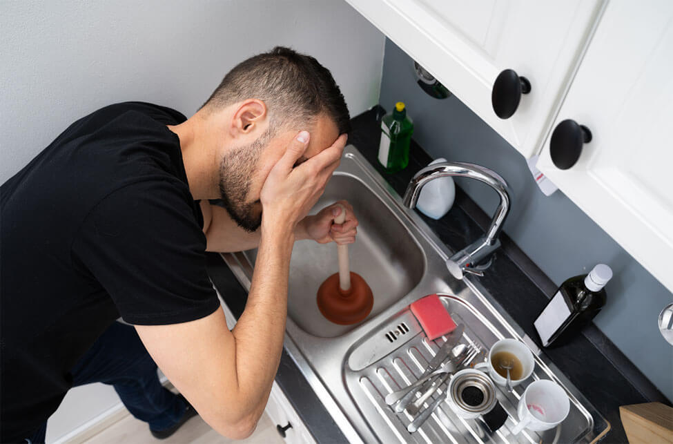 Homeowner using a plunger to clear a slow-draining sink