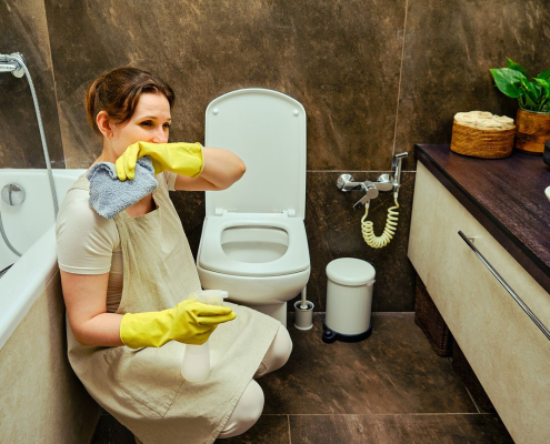 Woman cleaning a bathroom while dealing with unpleasant odours